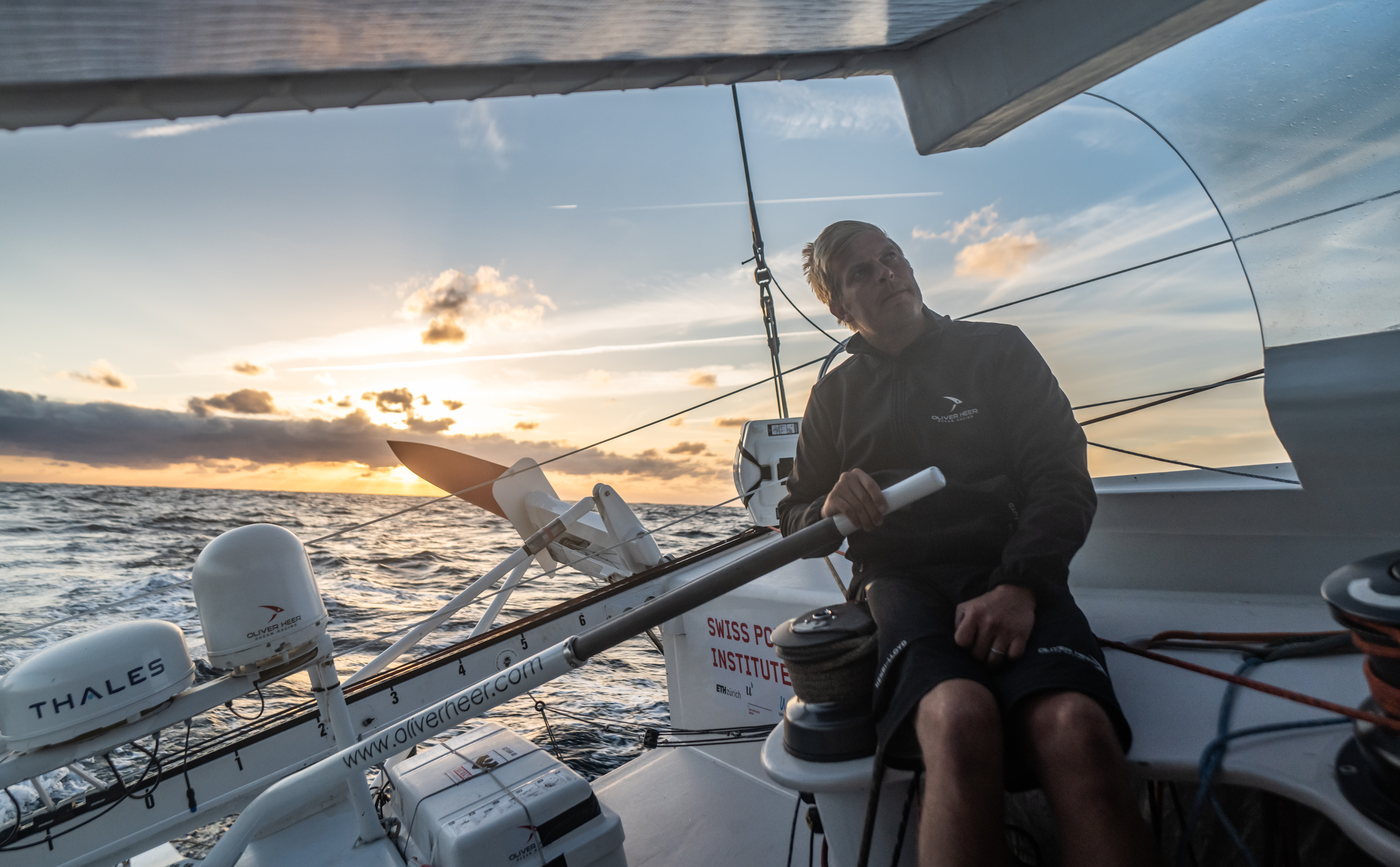 Skipper Oliver Heer steering his sailing boat with SPI logo in the background